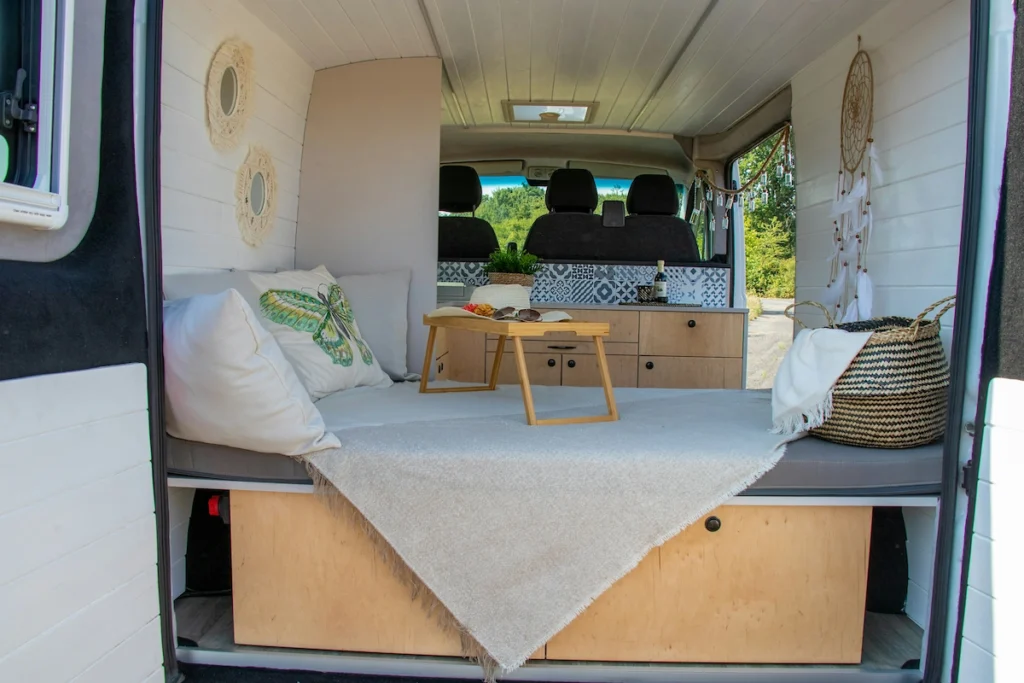 A picture of small camper van interior. There is only a bed a small cabinet inside it. Due to limited space there is no space for any kitchen, refrigerator or any other modern conveniences.