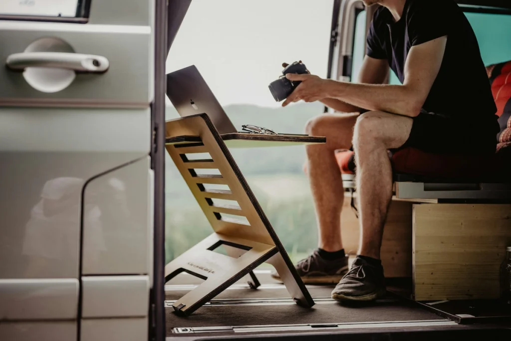 A digital nomad working on his laptop inside his van.