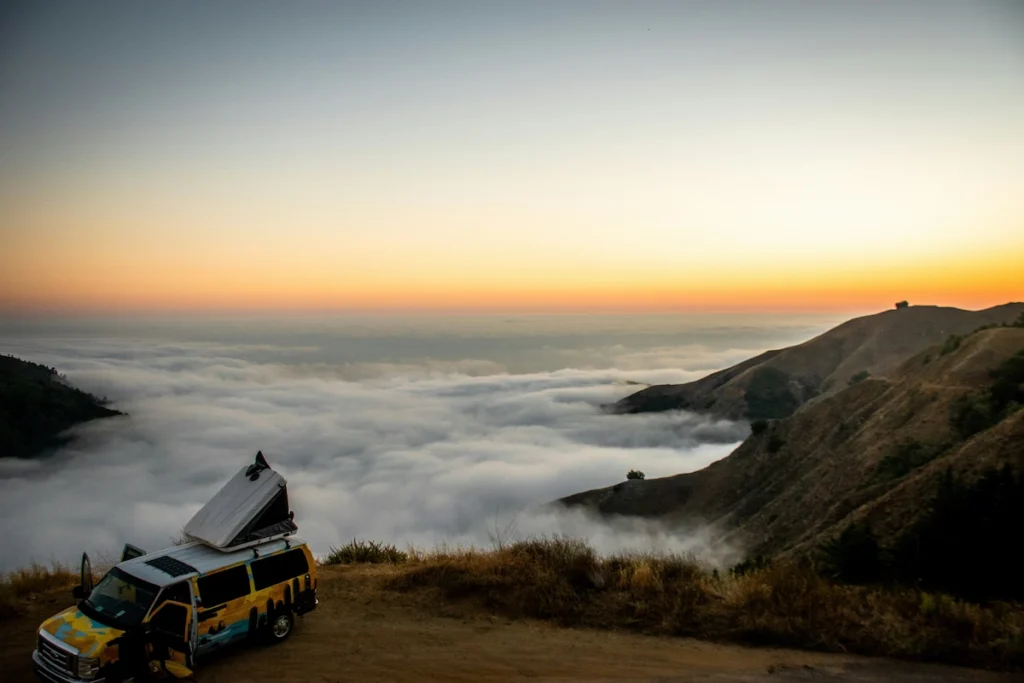 A picture of a camper van parked on high cliff - which is a tourist attraction. 