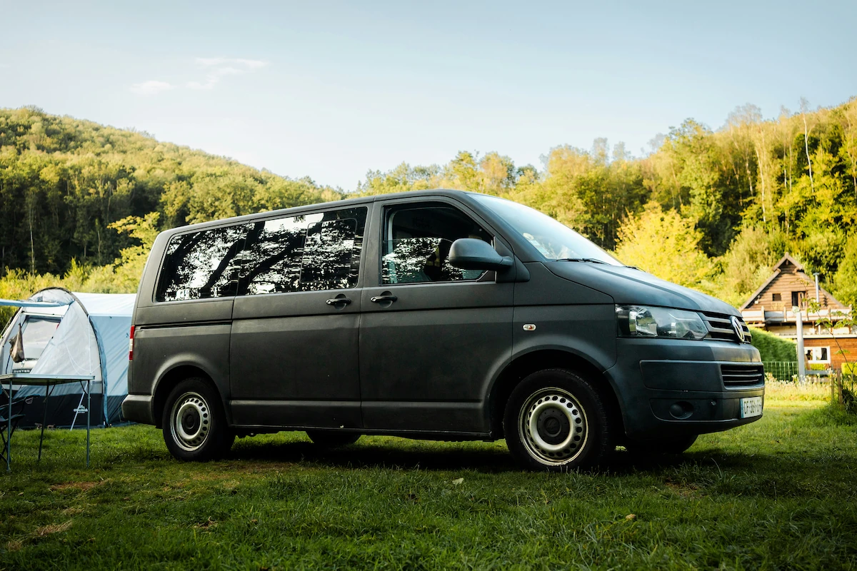 A camper minivan parked in a park.