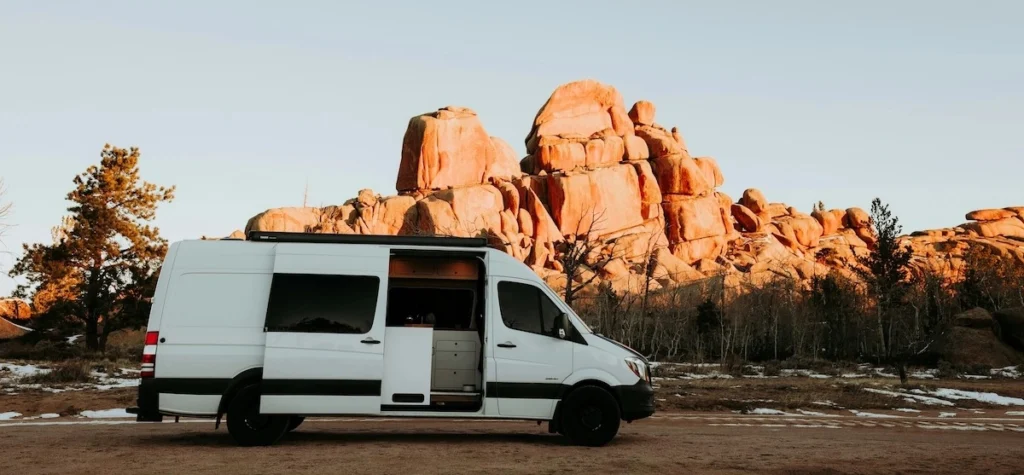 A camper van with a cozy van life set-up parked in a beautiful rocky desert landscape.