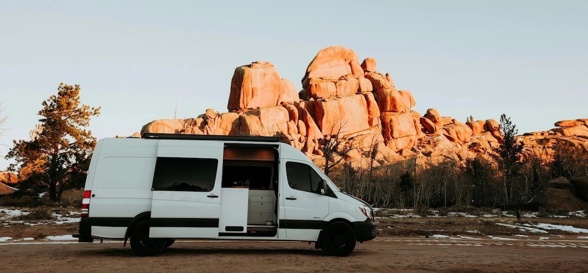 A camper van with a cozy van life set-up parked in a beautiful rocky desert landscape.