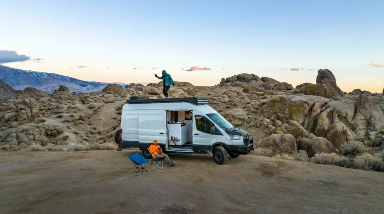 A photo of a high-roof ford transit camper van parked in a mountain landscape.